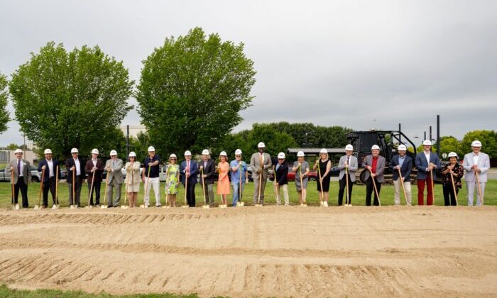 line of people in hard hats with shovels for a groundbreaking