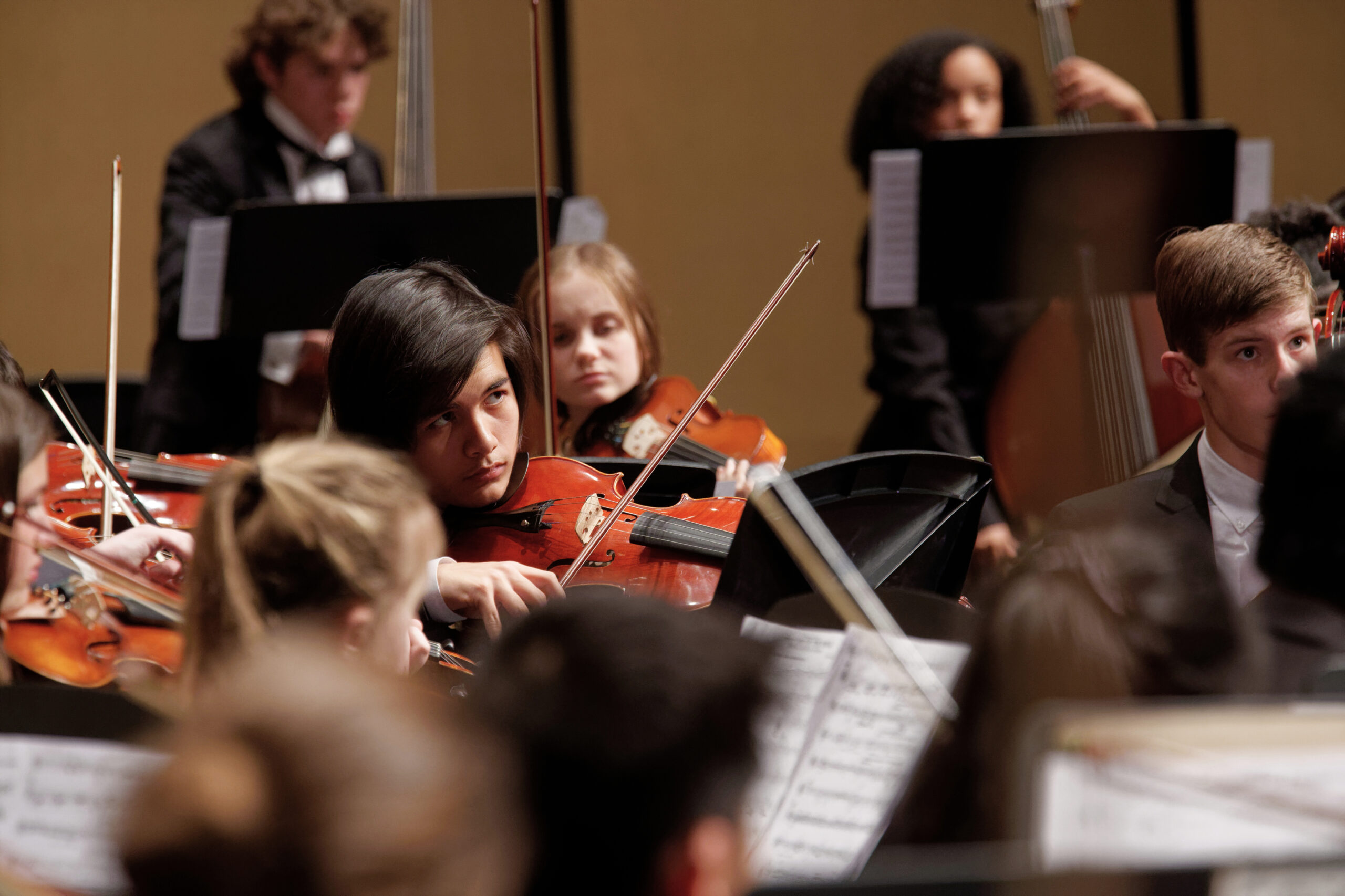 close up view of young people playing violin in an orchestra
