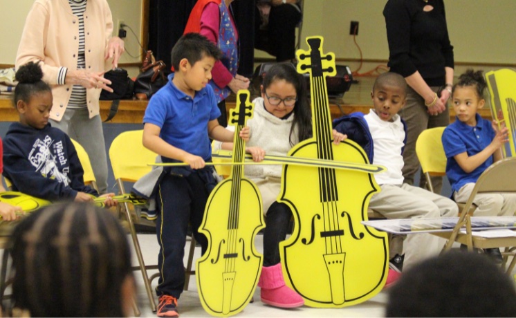 young boy playing a simulated yellow cello