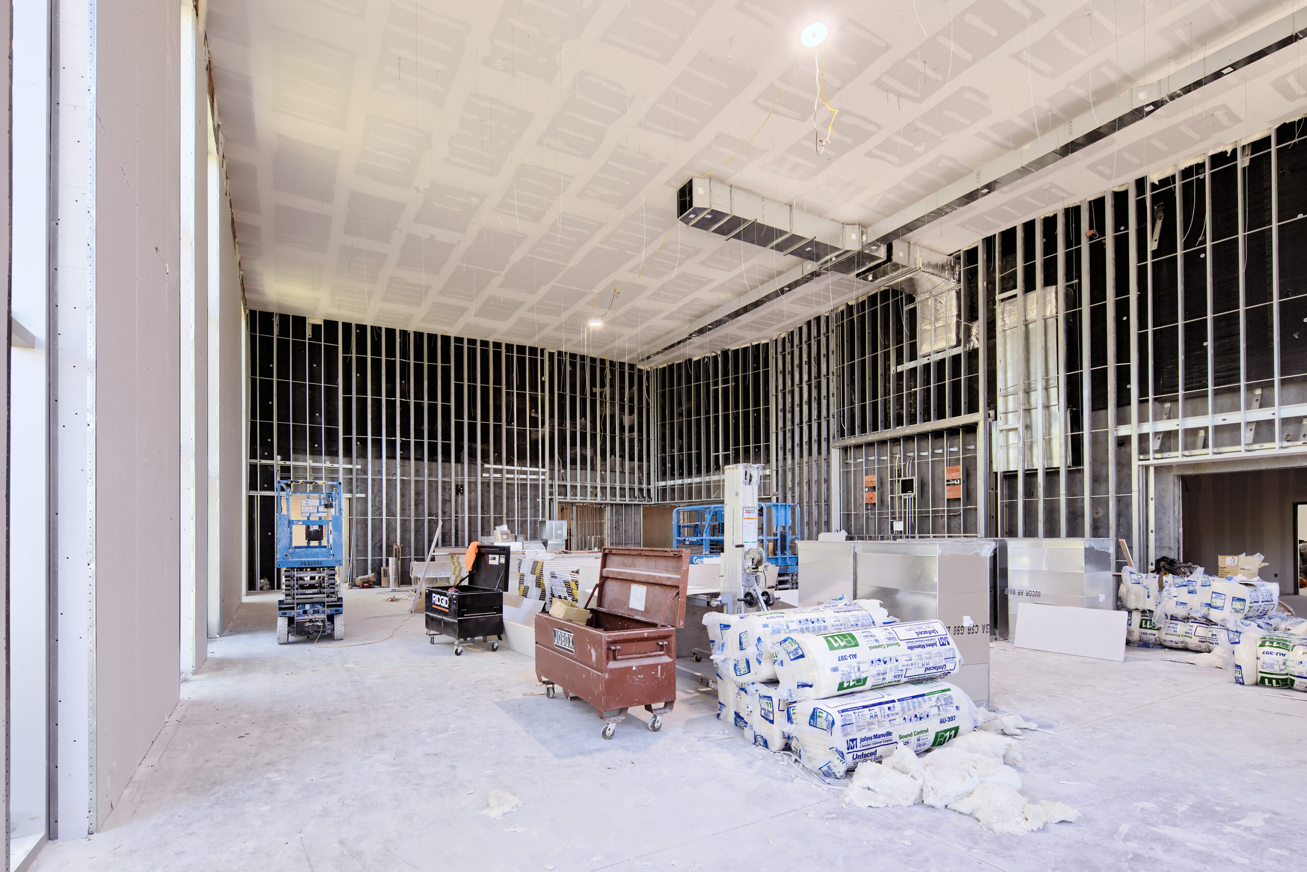 Building under construction. Interior, large room with tiled ceiling, stacks of construction material and tools.